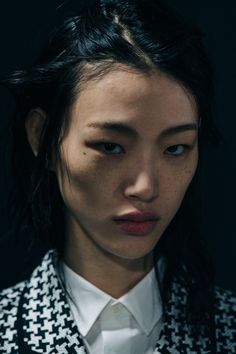 a woman with black hair wearing a white shirt and jacket, looking at the camera