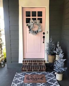 a pink door with a welcome mat on the front porch