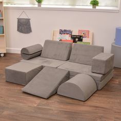 a gray couch sitting on top of a wooden floor next to a book shelf filled with books