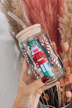 a person holding up a glass jar with candy canes and candies on it