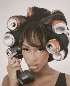 a woman holding a cell phone to her ear with cans on top of her head