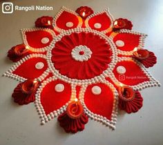 a red and white decorative item with beads on it's sides, sitting on a table