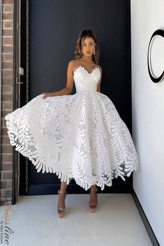 a woman standing in front of a door wearing a white dress