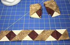 two pieces of fabric sitting on top of a blue cutting mat next to a white object