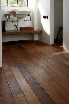 a bathroom with wood flooring and white walls in the background is an open window