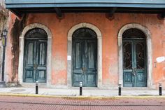 an old building with two blue doors on the front and one green door on the back