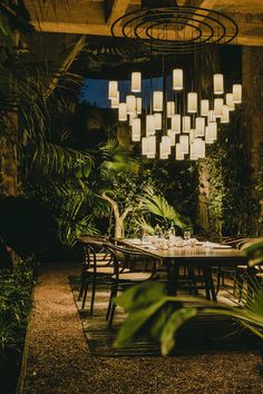 an outdoor dining area with tables and chairs lit up by hanging lanterns in the dark