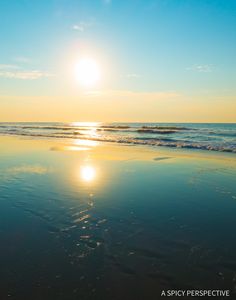 the sun is setting over the water at the beach