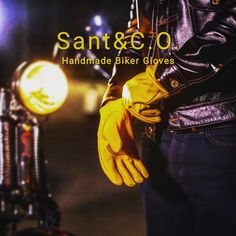 a man wearing yellow gloves standing next to a motorcycle with the words sant & e o on it