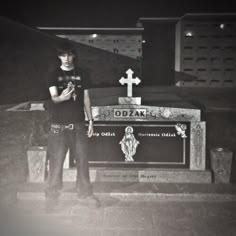 a young man standing in front of a grave with a cross on it's head