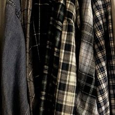 several plaid shirts are hanging on a rack