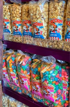 there are many bags of popcorn on the shelf in the store and one bag is filled with candy