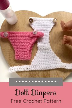 two crocheted baby diapers sitting on top of a heart shaped wooden tray