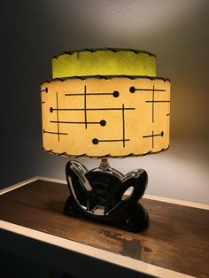 a lamp that is sitting on top of a wooden table in front of a wall