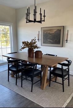 a dining room table with black chairs and a plant in a vase on top of it