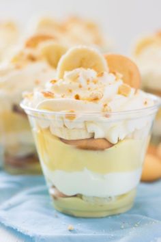 banana cream trifle dessert in a plastic cup on a blue cloth with bananas around it