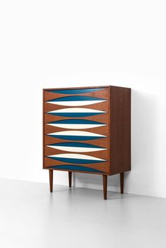 a wooden cabinet with blue and white stripes on it's sides, against a white wall