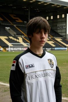 a young man standing on top of a soccer field wearing a white and black uniform