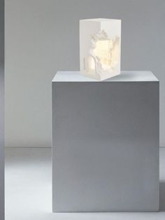 a white sculpture sitting on top of a gray block in the middle of a room