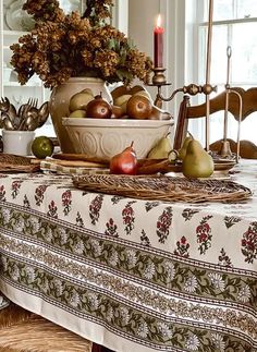 a table topped with a bowl of fruit next to a candle