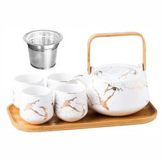 a tea set with four cups and a strainer on a wooden tray, ready to be served