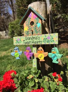 a wooden birdhouse with flowers in the foreground and a sign that says grandma's tweet hearts