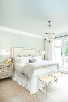 a bedroom with a large bed and white furniture in it's center area, along with a chandelier hanging from the ceiling