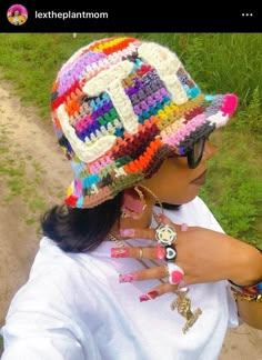 a woman wearing a multicolored crocheted hat and ring on her finger