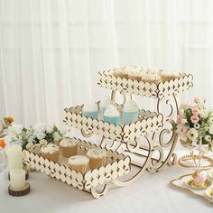 two tiered cake stand with cupcakes on it and flowers in the background