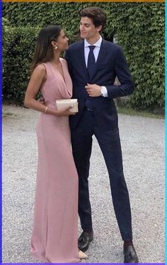 a man in a suit and tie standing next to a woman wearing a pink dress