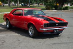 a red and black muscle car parked in a parking lot