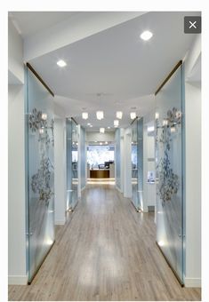 an empty room with wood floors and glass walls on the wall is lit by recessed lights