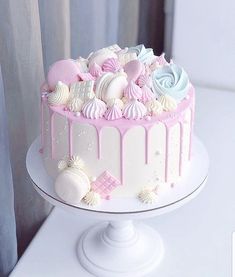 a white cake with pink icing and seashells on the top is sitting on a pedestal