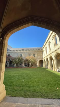 an archway leading to a building with grass in the foreground