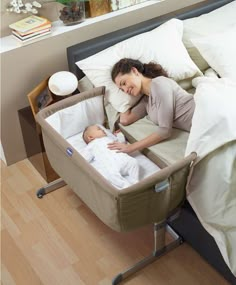 a woman laying on top of a bed next to a baby in a crib