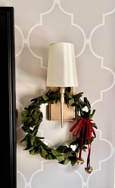 a christmas wreath hanging on the wall next to a lamp