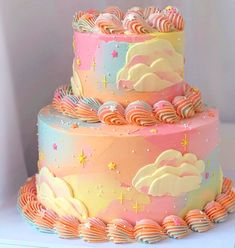 there is a multi layer cake with clouds and stars on the top, in pastel colors