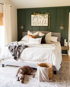 a dog laying on top of a white bed in a bedroom next to a window