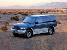 a blue suv parked in the desert with mountains in the background