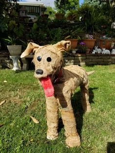 a dog statue made out of cardboard sitting in the grass with its tongue hanging out