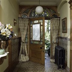 an entry way with a wooden door and floral arrangement on the table in front of it