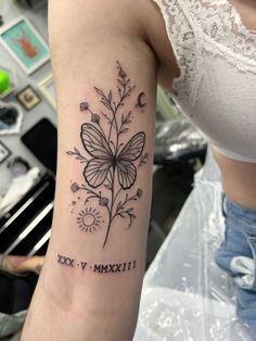 a woman's arm with a butterfly and flowers tattoo on the left side of her arm