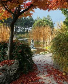 the path is lined with red and yellow leaves, along with a statue in the background