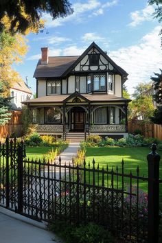 a house with a black iron fence in front of it and flowers on the lawn