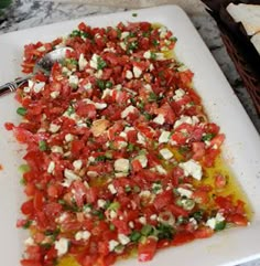 a white cutting board topped with sliced tomatoes and feta cheese on top of it