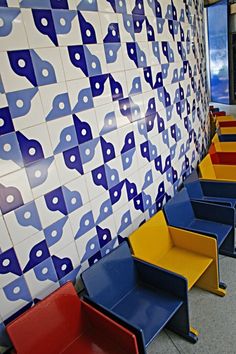 brightly colored chairs are lined up against a wall with blue and yellow designs on it