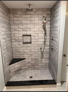 a walk in shower sitting next to a tiled wall