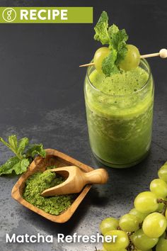 a green smoothie with grapes and mint on the side next to a wooden spoon