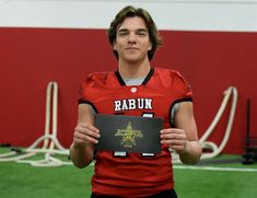 a young man holding up a plaque in front of him