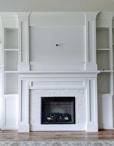 an empty living room with white bookcases and a fireplace